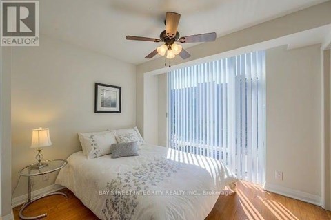 A bedroom with a bed, a ceiling fan, and a window with blinds.