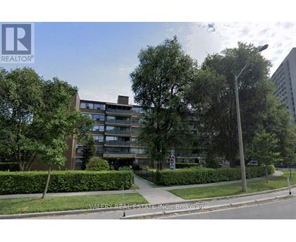 A street view of a residential area with apartment buildings and greenery.