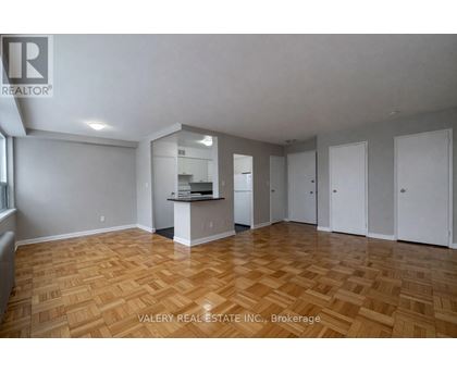 A spacious room with wooden flooring and white walls.