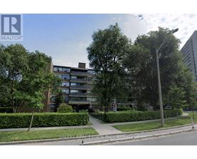 A street view of a residential area with apartment buildings and greenery.