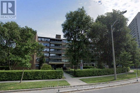 A street view of a residential area with apartment buildings and greenery.