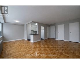 A spacious room with wooden flooring and white walls.