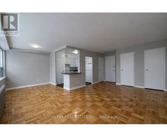 A spacious room with wooden flooring and white walls.
