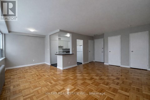 A spacious room with wooden flooring and white walls.