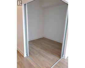 A room with a wooden floor and white walls, with a doorway open to another room.