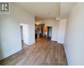 A room with wooden flooring and white walls, with a doorway leading to another room.