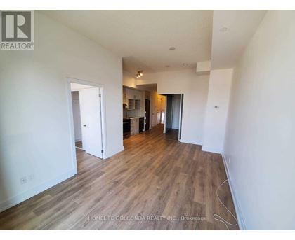 A room with wooden flooring and white walls, with a doorway leading to another room.