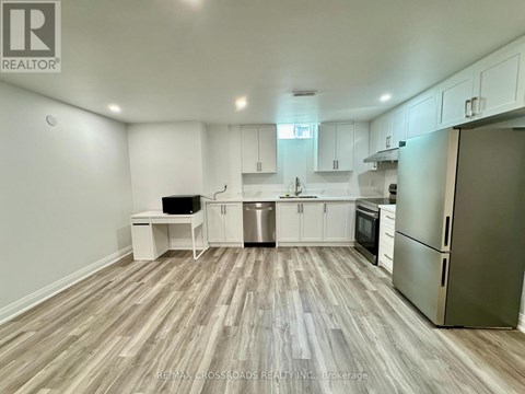 A kitchen with white cabinets and a wooden floor.