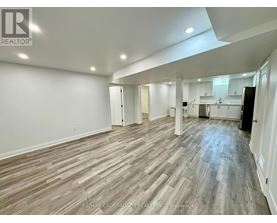 A spacious room with wooden flooring and white walls.