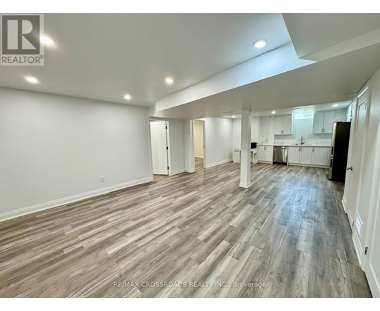 A spacious room with wooden flooring and white walls.