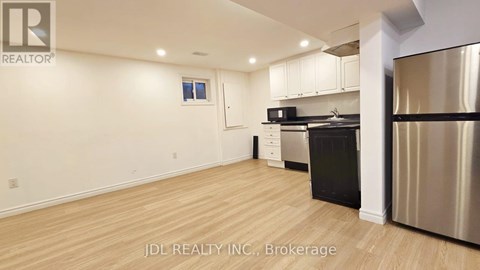 A kitchen with stainless steel appliances and wooden flooring.