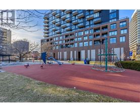 A playground with a red surface and a green swing set.