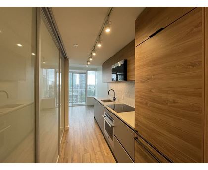 A modern kitchen with wooden cabinets and a glass door.
