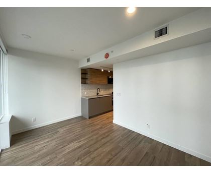 A room with a kitchen area in the background.