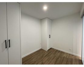 A room with a white door and a brown floor.