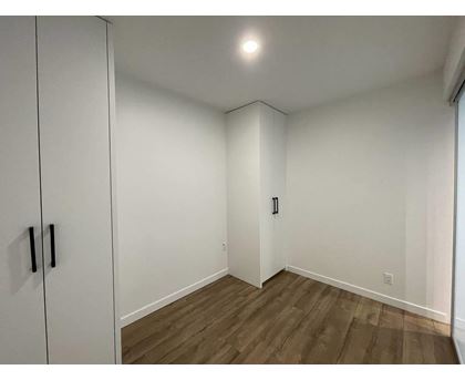 A room with a white door and a brown floor.