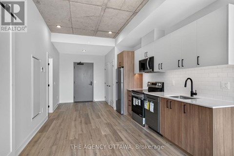 A kitchen with white cabinets and a wooden floor.