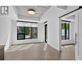 A real estate agency in Ottawa is showcasing a spacious and well-lit room with a view of the outdoors.