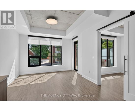 A real estate agency in Ottawa is showcasing a spacious and well-lit room with a view of the outdoors.