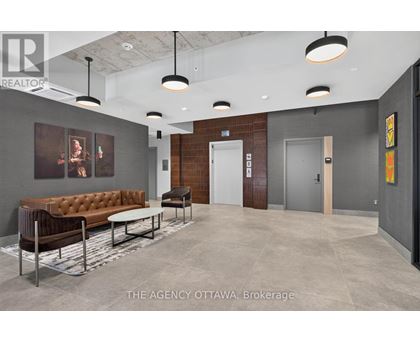 A modern office lobby with a brown leather sofa and a grey carpet.