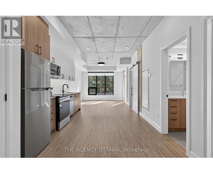 A modern kitchen with wooden floors and stainless steel appliances.