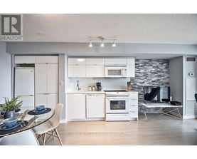 A modern kitchen with white appliances and a glass table.