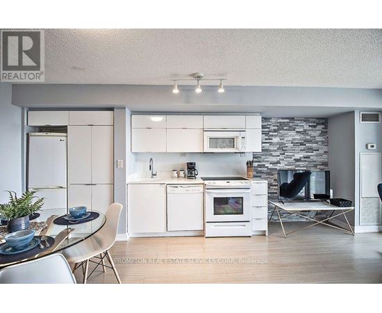 A modern kitchen with white appliances and a glass table.