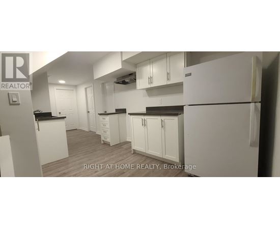 A white kitchen with a refrigerator, cabinets, and a counter.