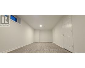 A spacious room with white walls and a wooden floor.