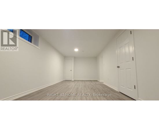 A spacious room with white walls and a wooden floor.