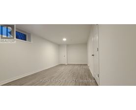 A spacious room with wooden flooring and white walls, with a door on the right side.