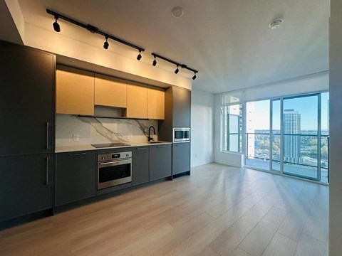 A modern kitchen with wooden cabinets and a large window overlooking the city.