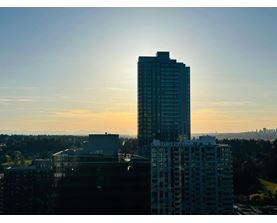 A tall building stands in the foreground with a sunset in the background.