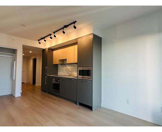 A modern kitchen with wooden floors and stainless steel appliances.