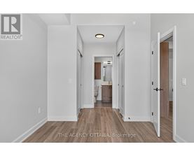 A hallway with a door on the right and a kitchen visible in the distance.