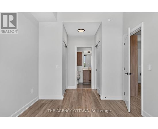 A hallway with a door on the right and a kitchen visible in the distance.