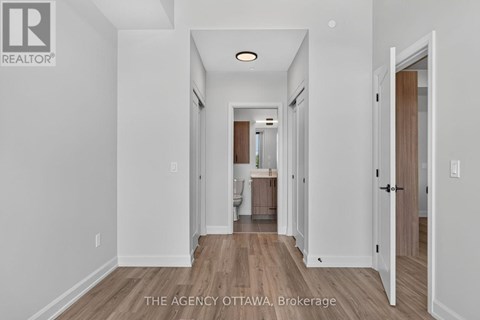 A hallway with a door on the right and a kitchen visible in the distance.