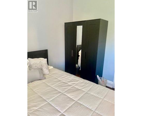A bedroom with a white bed and a black wardrobe.