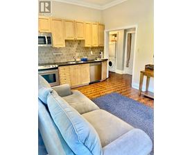 A kitchen with wooden cabinets and a grey couch.