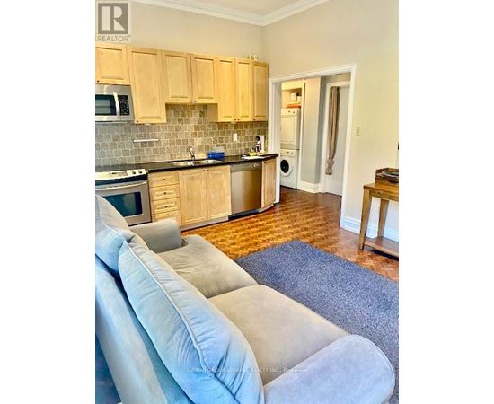 A kitchen with wooden cabinets and a grey couch.