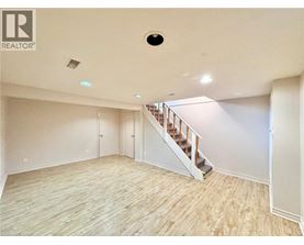 A spacious room with wooden flooring and a staircase leading to another level.