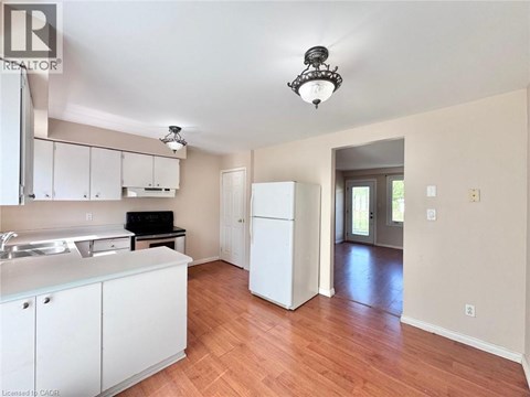 A kitchen with white cabinets and a wooden floor.