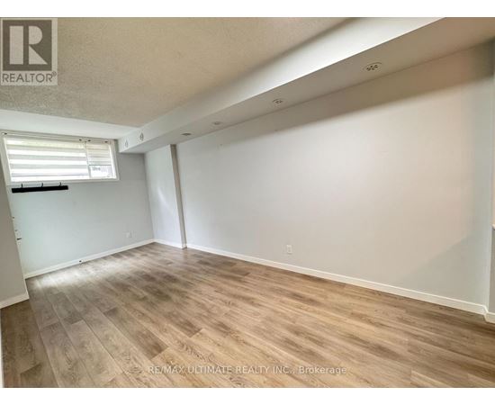 A room with wooden flooring and white walls, with a window on the left side.