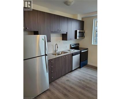 A modern kitchen with a stainless steel refrigerator and dark wood cabinets.