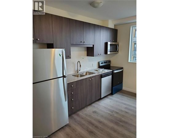 A modern kitchen with a stainless steel refrigerator and dark wood cabinets.