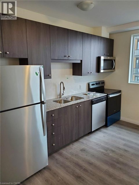 A modern kitchen with a stainless steel refrigerator and dark wood cabinets.