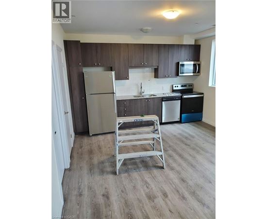 A kitchen with a refrigerator, stove, and microwave.