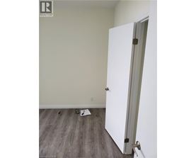 A white door is open in a room with wood flooring.