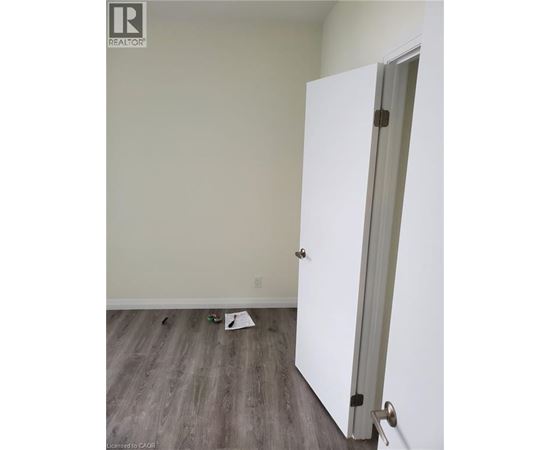 A white door is open in a room with wood flooring.