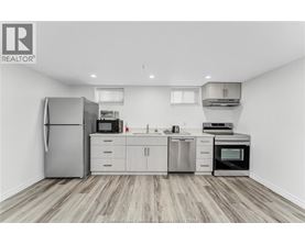 A kitchen with a refrigerator, microwave, oven, and sink.